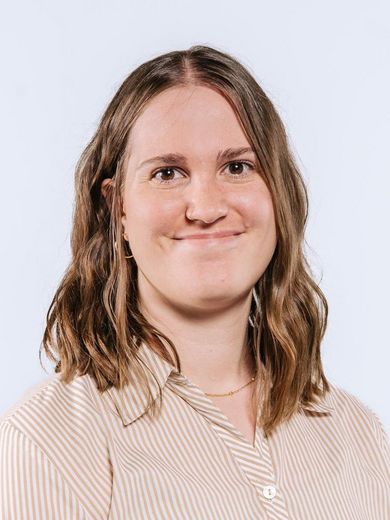 Auf dem Bild ist Viktoria Janke zusehen. Sie hat dunkelblondes, schulterlanges Haar und trögt eine orange, weiße Bluse. 