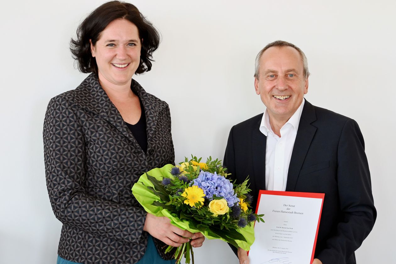 Frau und Mann l&auml;cheln in die Kamera. Sie halten einen Blumenstrau&szlig; und eine Urkunde.