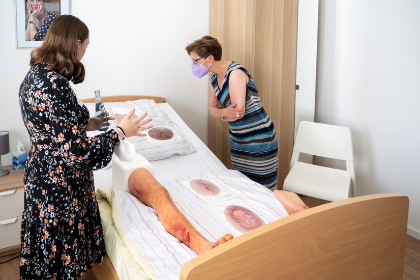 Eine Studentin zeigt Wissenschaftssenatorin Dr. Claudia Schilling künstliche Wunden in einem Krankenbett im Skills Lab der HSB.