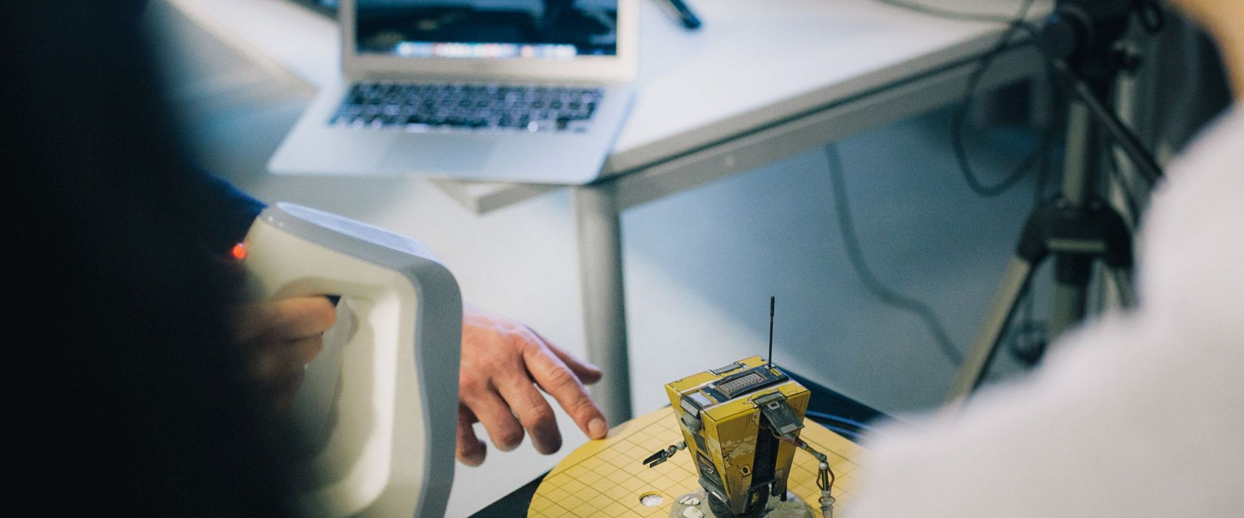 Studierende scannen ein Robotermodell mit einem 3D-Scanner. 