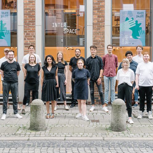 Gruppe Studierender stehen mit Abstand vor Geb&auml;ude