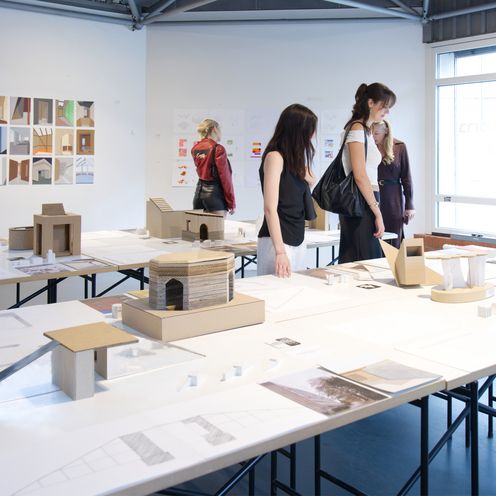 Pesonen schauen sich Bilder und Modelle auf Tischen an