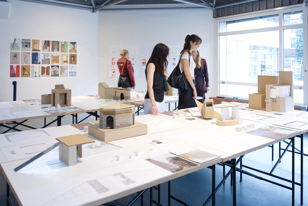 Pesonen schauen sich Bilder und Modelle auf Tischen an