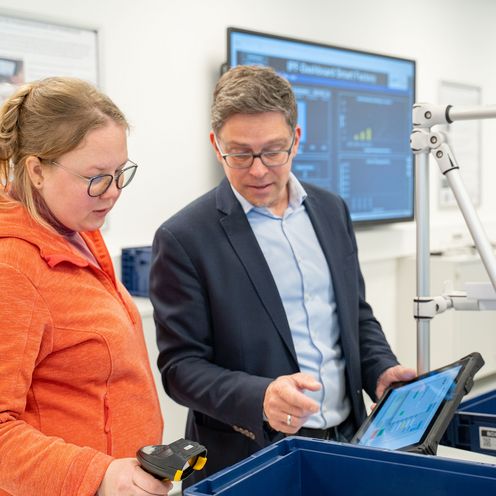 Junge Frau und Mann schauen auf ein Tablet.