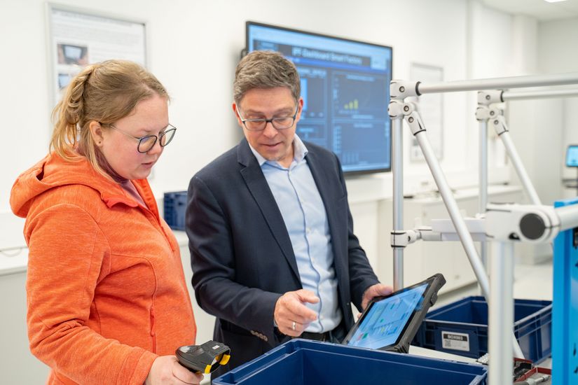 Junge Frau und Mann schauen auf ein Tablet.