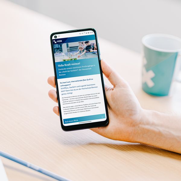 Kampagnenbild #aufzurHSB Studierendenmarketing Hand mit Smartphone und Abbildung der Webseite