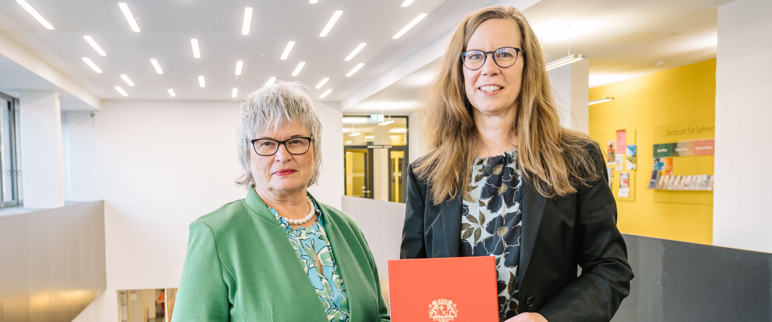 Prof. Dr. Daniela Konrad mit Rektorin Bild mit zwei Frauen, die rechte hält eine rote Urkunde.
