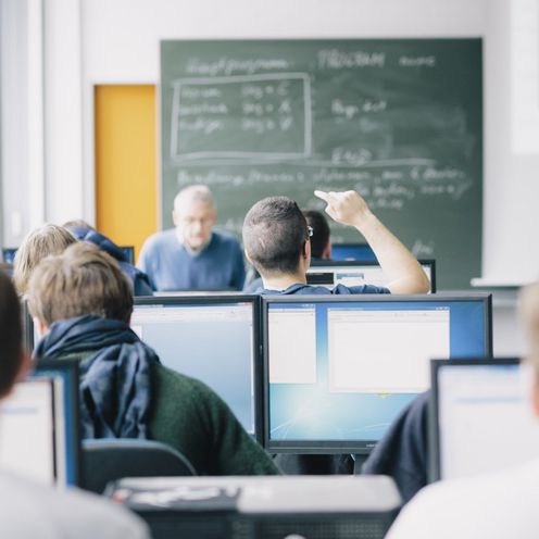 Studierende sitzen an Computern in einem Seminarraum.