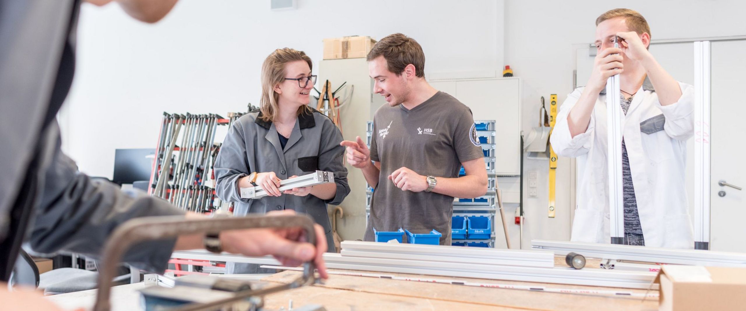 Eine Gruppe Studierende arbeitete an metallischen Bauteilen in einer Werkstatt.