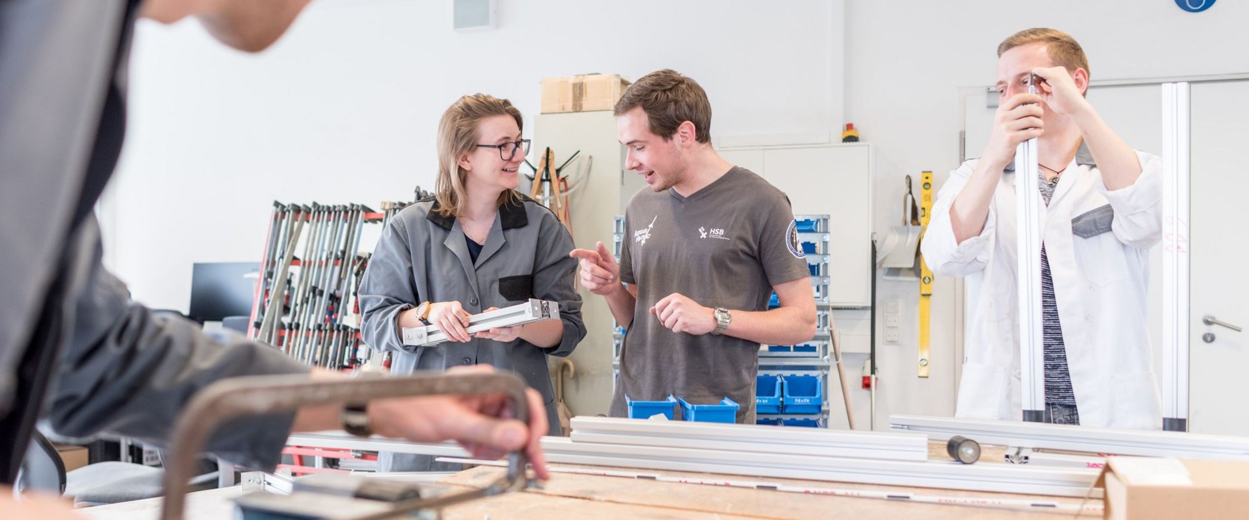 Eine Gruppe Studierende arbeitete an metallischen Bauteilen in einer Werkstatt.