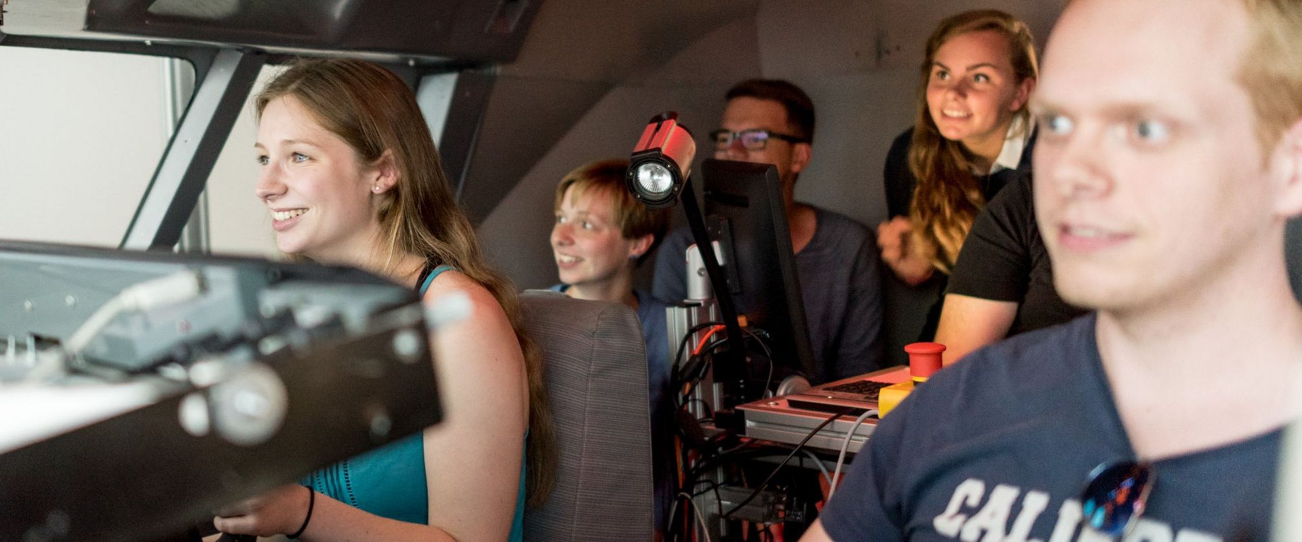 Studierende sitzen im Cockpit eines Flugsimulators.