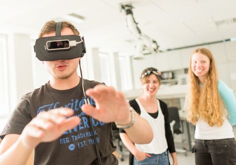 Student mit VR Brille. Er streckt seine Hände Richtung Kamera.