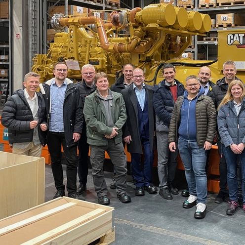 Die Mitglieder der Peergroup DIGIVER posieren vor einem großen Motor