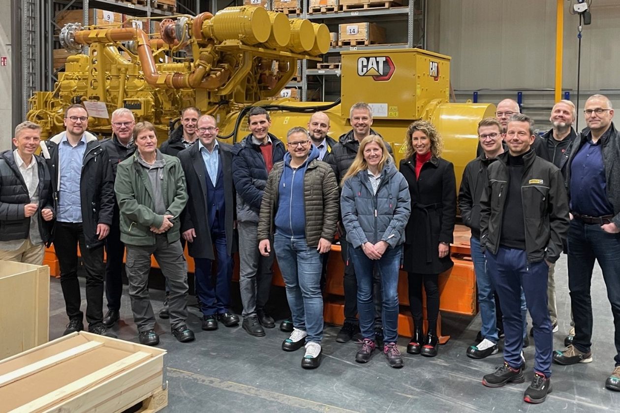 Die Mitglieder der Peergroup DIGIVER posieren vor einem großen Motor