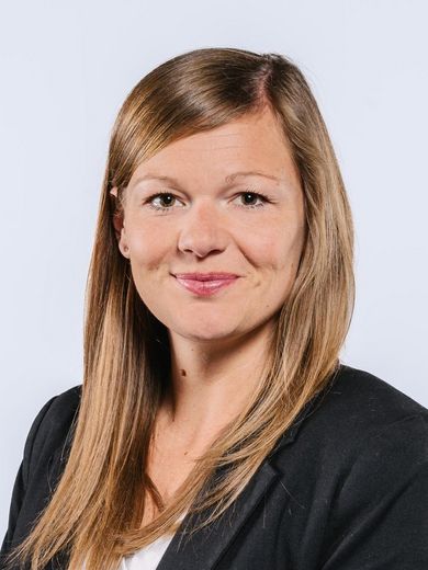 Auf dem Bild ist Gina Wagener zusehen. Sie hat langes, blondbraunes Haar und trägt eine weiße Bluse unter einem schwarzen Blazer. 