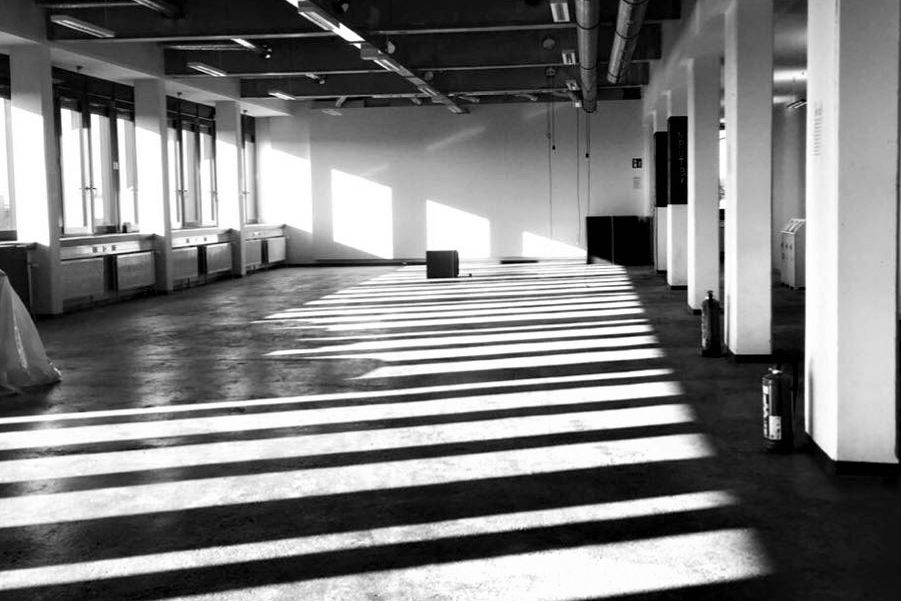 Ein großer leerer Raum mit vielen harten Schatten von Fenstern auf dem Boden. 