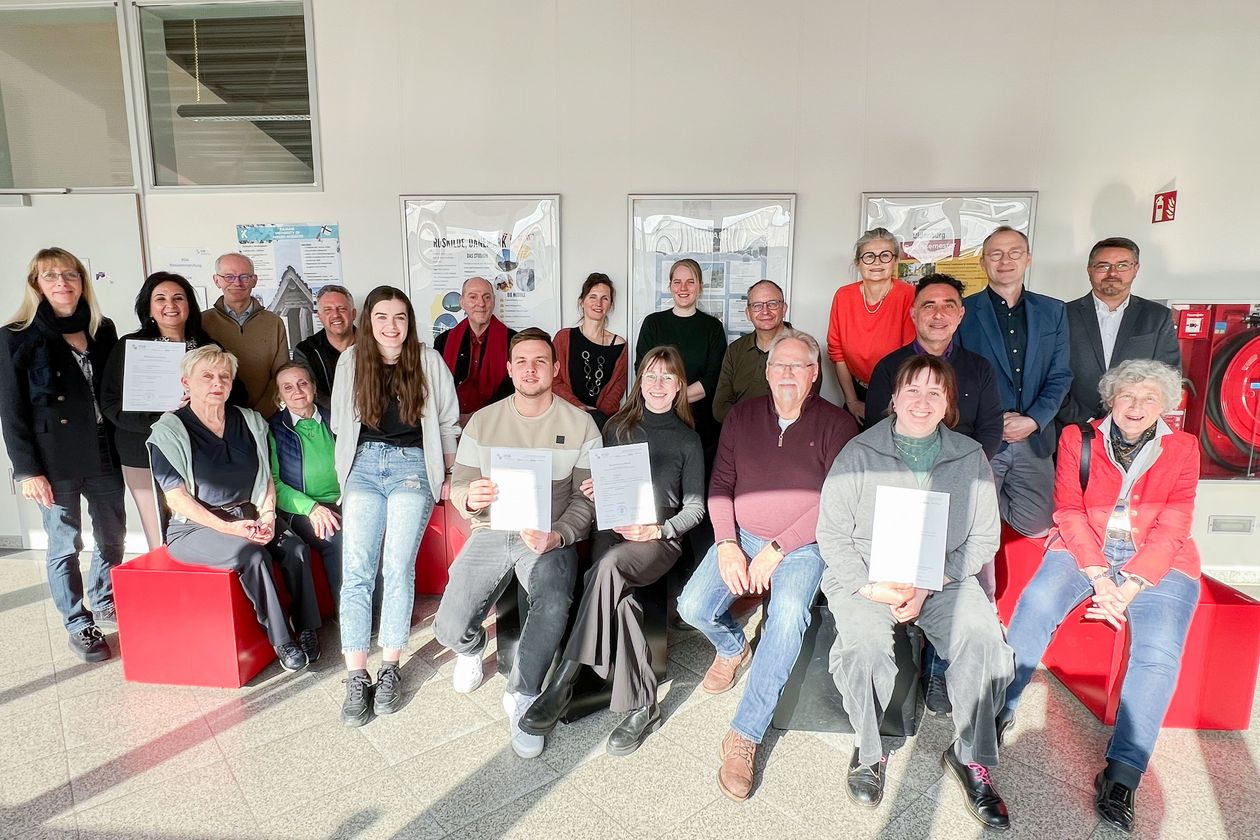 Reiseleiterzertifikat Das Bild ist ein Gruppenfoto aller frisch zertifizierten Reiseleiter. Alle Personen halten ein Zertifikat in der Hand und lächeln in die Kamera.