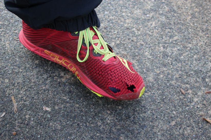 Ein roter kaputter Laufschuh auf einer Stra&szlig;e.