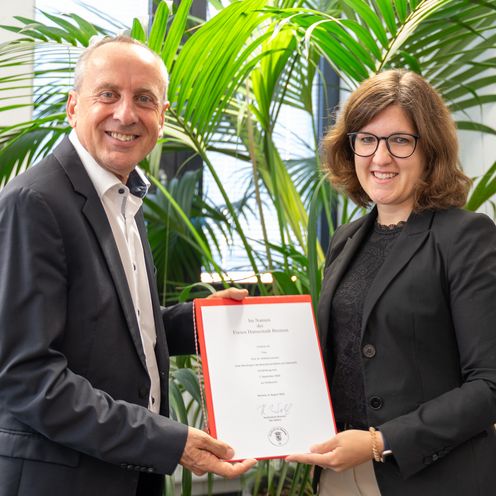 Mann und Frau halten gemeinsam eine Urkunde und lachen in die Kamera