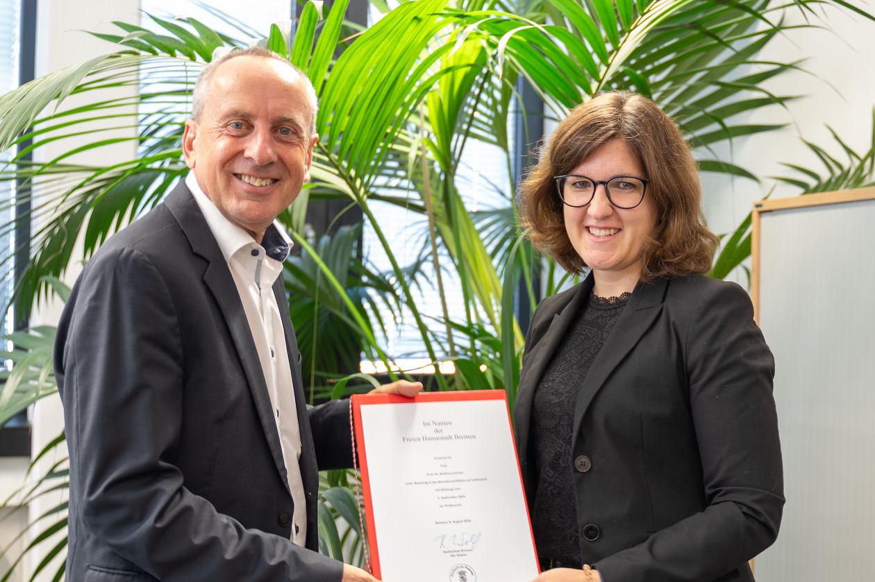 Mann und Frau halten gemeinsam eine Urkunde und lachen in die Kamera