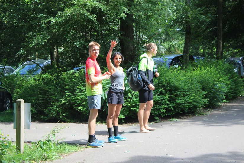 Drei Läufer stehen am Straßenrand.