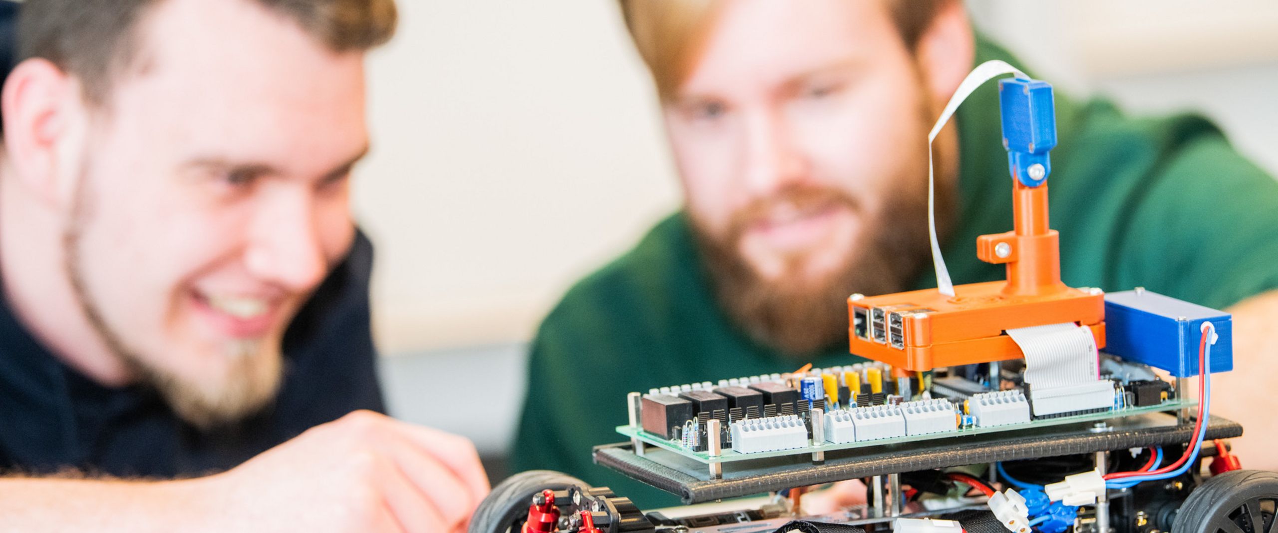 Zwei Studenten betrachten ein elektrisches Modellauto. 