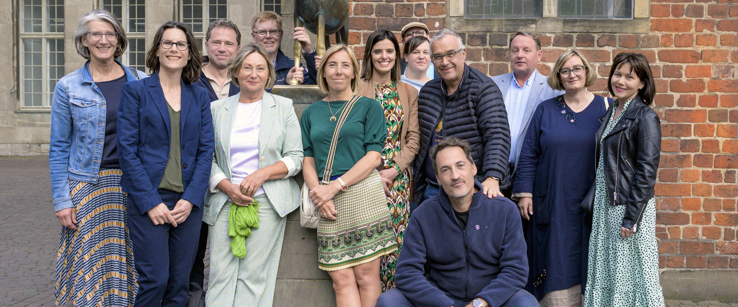 Gruppenbild mit Männern und Frauen an der Skulptur der Bremer Stadtmusikanten. 