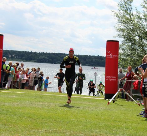 Schwimmer:innen in Neoprenanz&uuml;gen laufen beim M&uuml;ritz-Triathlon 2021 ans Ufer.