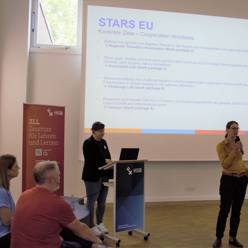 Frau steht an rednerpult und h&auml;lt Vortrag. Im Hintergrund ist eine Landkarte von Europa zu sehen.