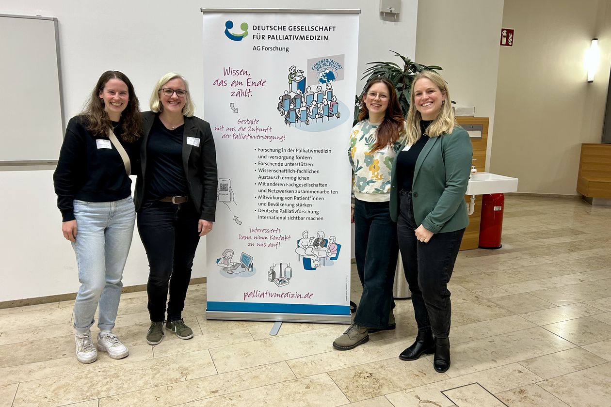 Gruppenbild mit vier Frauen. In der Mitte ein Roll-up