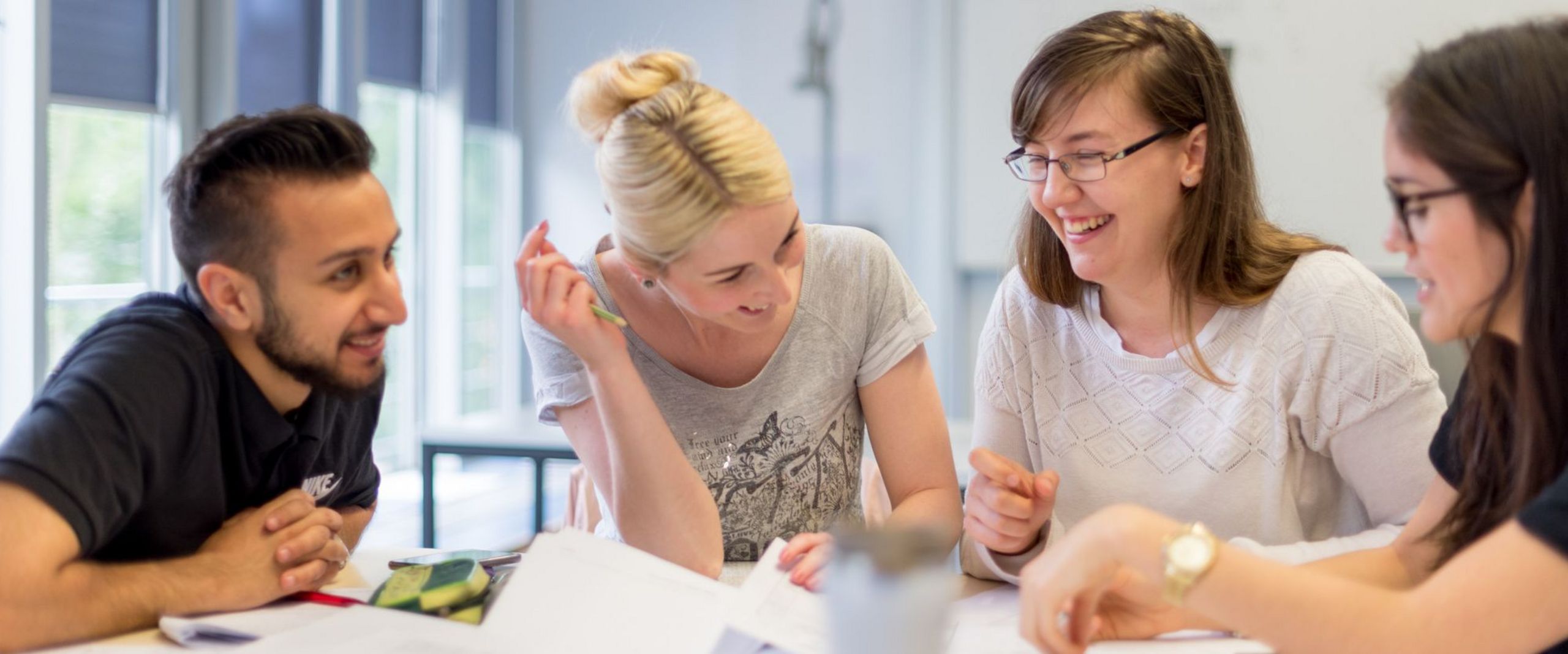 Eine Gruppe Studierender sitzt am Tisch und diskutiert.