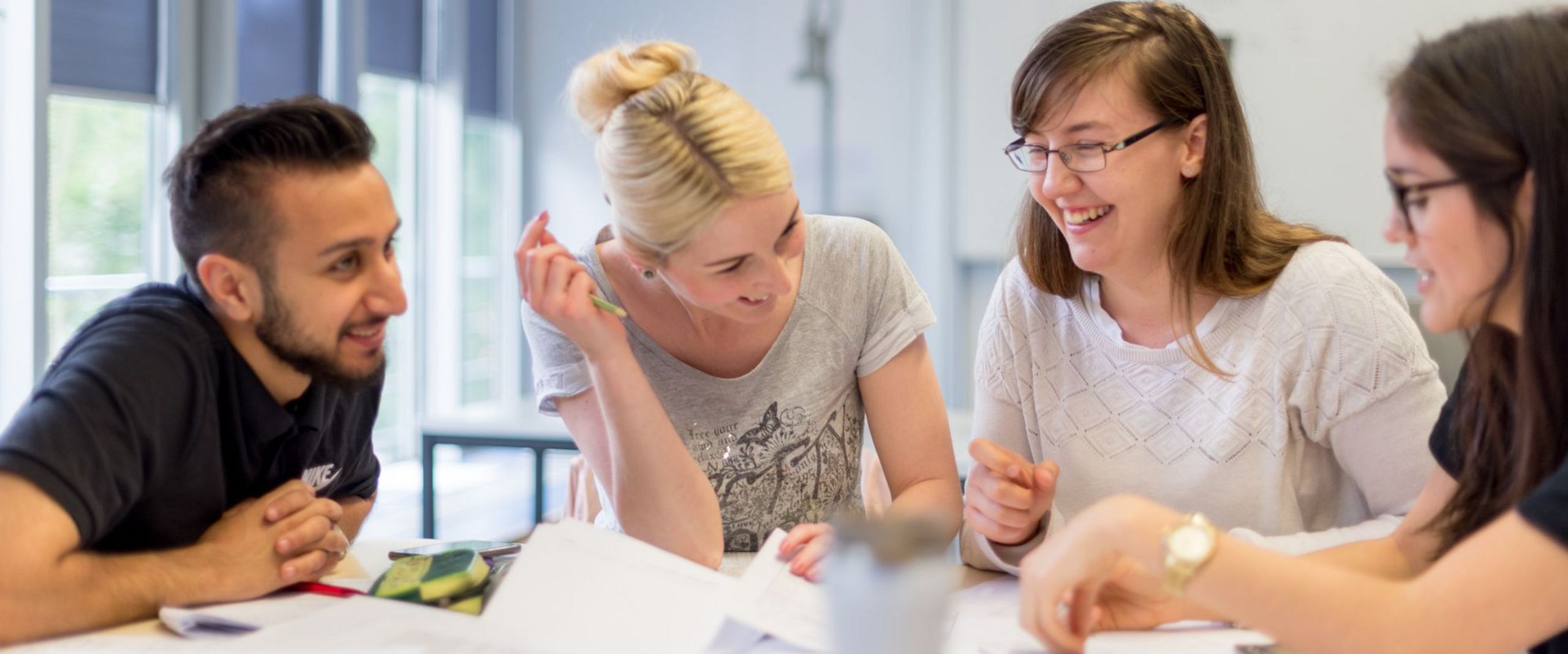 Eine Gruppe Studierender sitzt am Tisch und diskutiert.