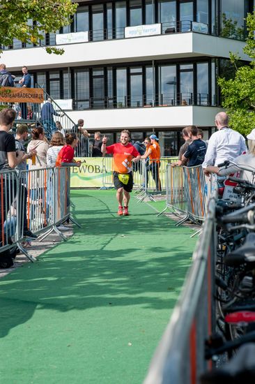 Ein l&auml;chelnder L&auml;ufer auf der Strecke und an der Seite stehen viele Zuschauer.
