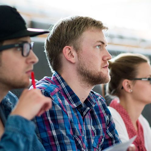 Drei Studierende sitzen im H&ouml;rsaal und gucken konzentriert nach vorne.