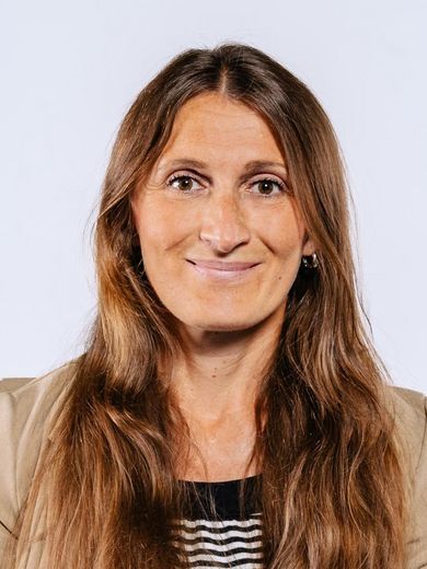 Auf dem Bild ist Vesna Warneke zusehen. Sie hat lange braune Haare und trägt ein schwarz-weiß gestreiftes T-Shirt unter einer beigen Jacke. 