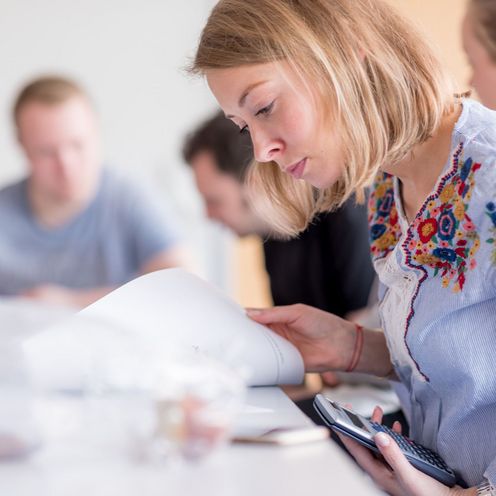 Eine Studentin beugt sich konzentriert &uuml;ber ihre Unterlagen in einem Seminar.