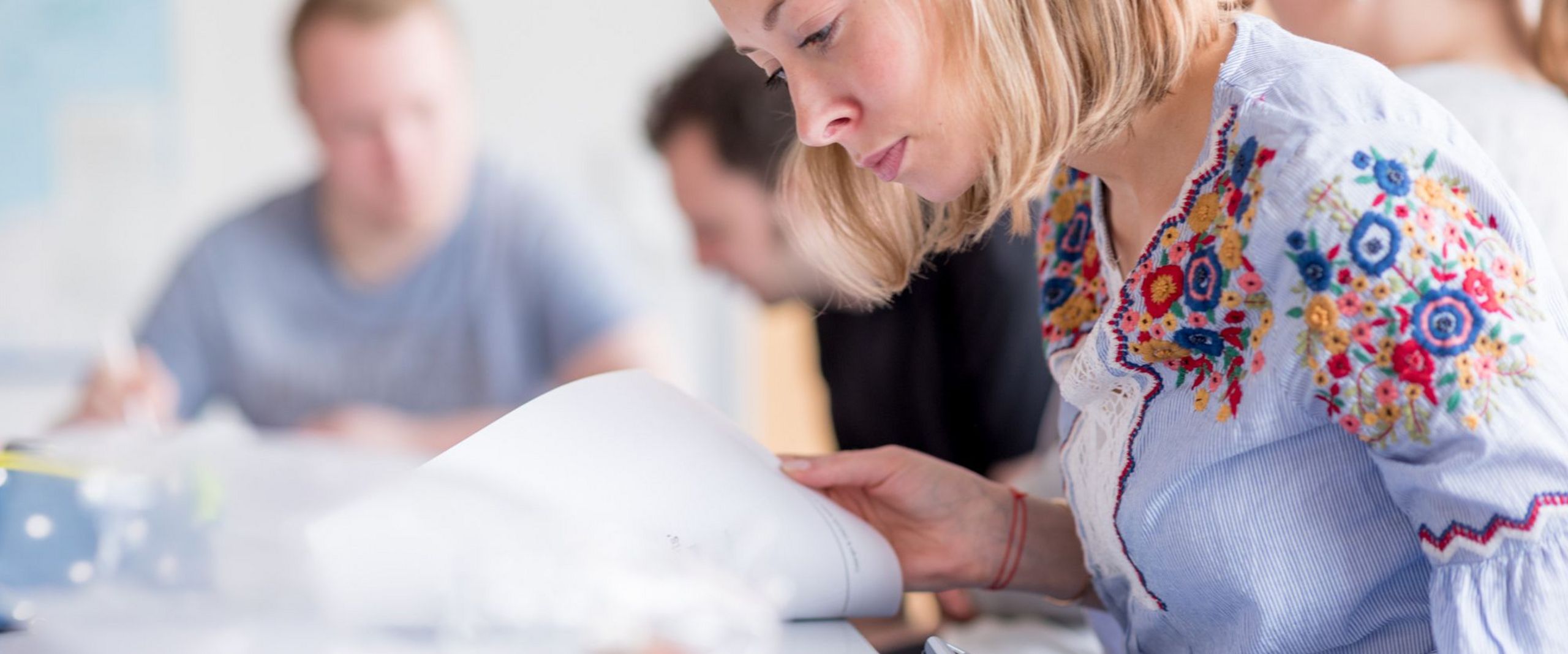 Eine Studentin beugt sich konzentriert über ihre Unterlagen in einem Seminar.