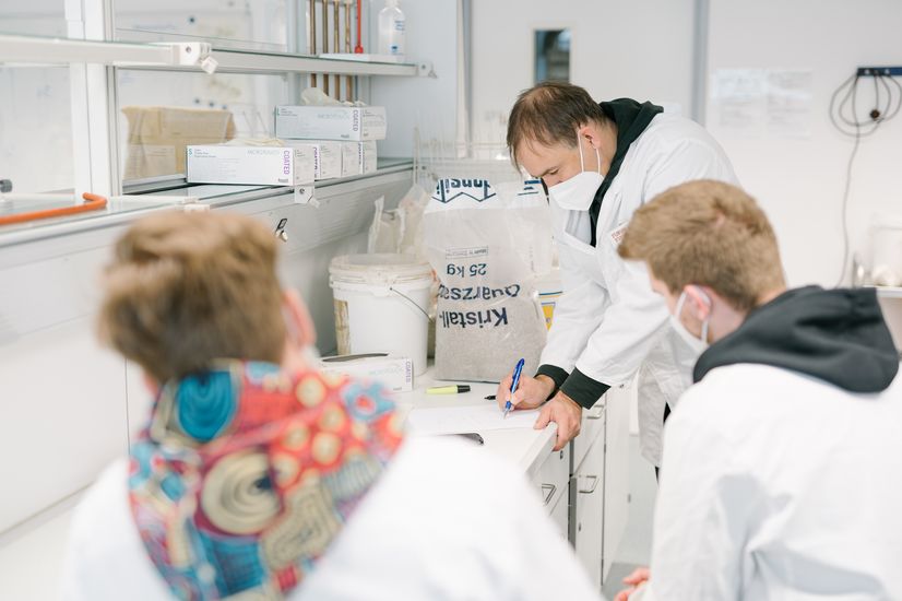 Zwei Studierende im Strömungslabor schauen dem Professor bei einem Experiment zu. 