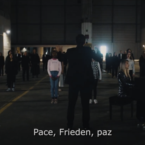 Gruppe von Menschen steht in einer dunklen Halle mit einem Klavierfl&uuml;gel