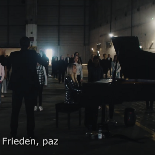 Gruppe von Menschen steht in einer dunklen Halle mit einem Klavierflügel