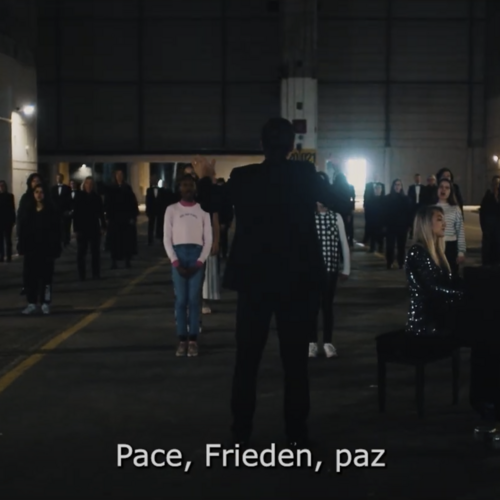 Gruppe von Menschen steht in einer dunklen Halle mit einem Klavierflügel