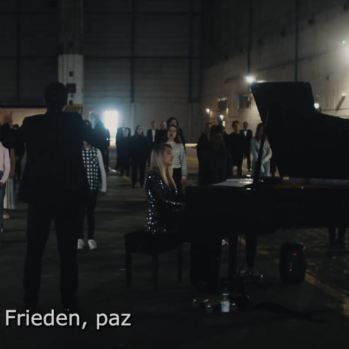 Gruppe von Menschen steht in einer dunklen Halle mit einem Klavierfl&uuml;gel