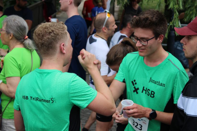 Zwei L&auml;ufer umgeben von vielen Personen geben sich die Hand.