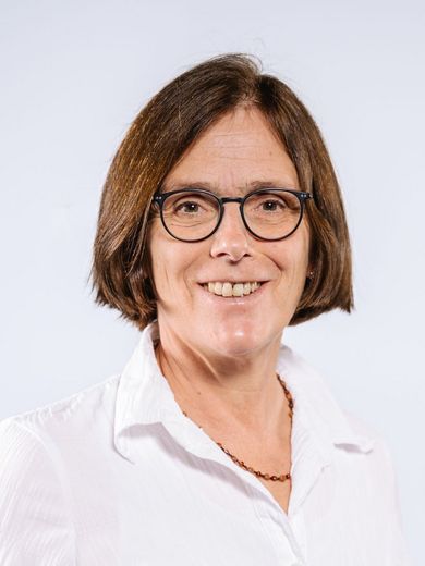 Auf dem Bild ist Heidi Hehlmann zu sehen. Sie hat kinnlanges, glattes braunes Haar. Sie trägt eine weiße Bluse und eine runde Brille.