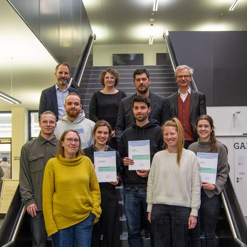 Gruppenbild mit M&auml;nnern und Frauen auf einer Treppe. Einige halten Urkunden