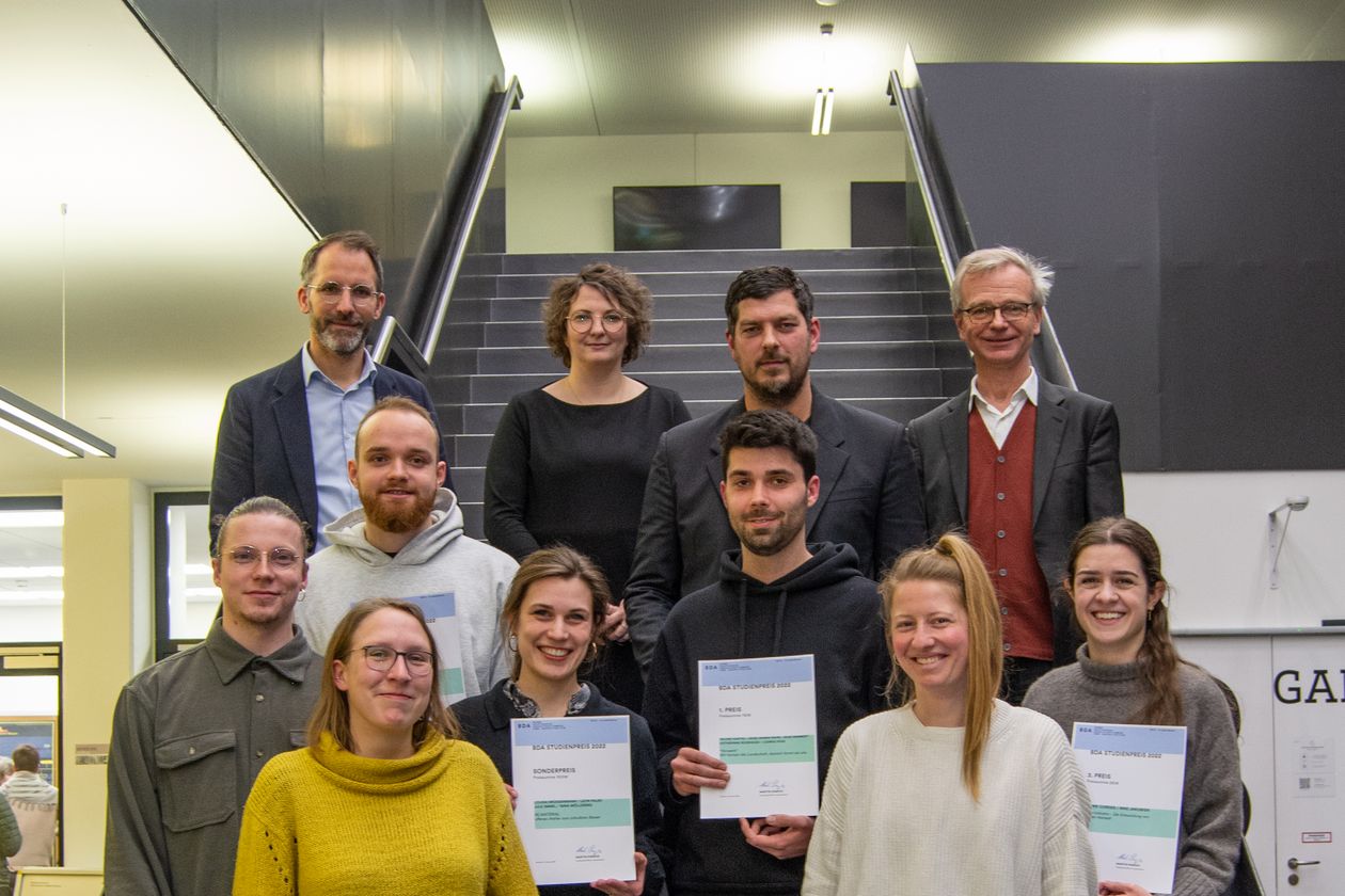 Gruppenbild mit M&auml;nnern und Frauen auf einer Treppe. Einige halten Urkunden