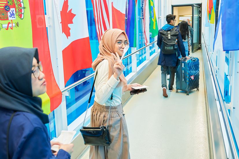 Internationale Studierende im Flur mit Gepäck und Flaggen