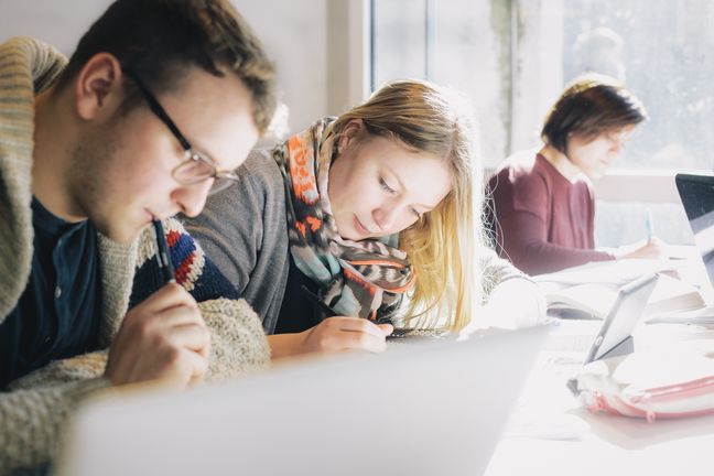 3 Personen die nebeneinander sitzen und Schreiben
