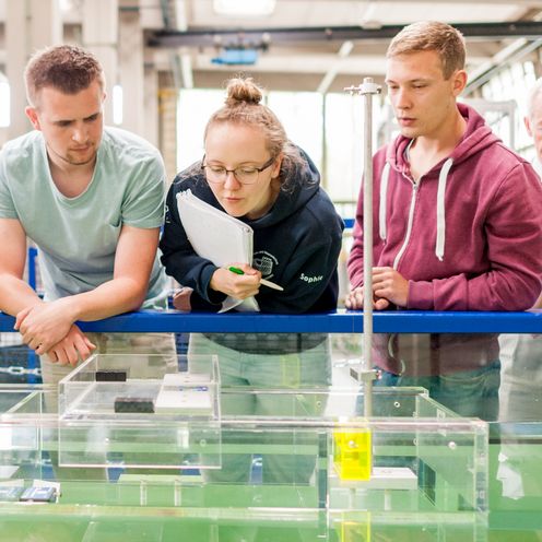 Studierende testen eine schwimmende Konstruktion in einem Wasserbecken.