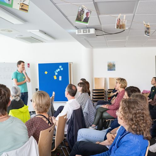 Auf dem Bild ist ein Vortragender zusehen, der mit dem Publikum interagiert. 